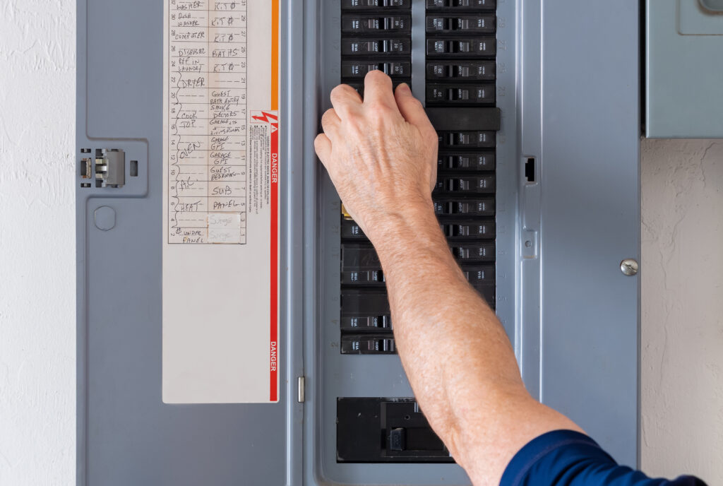 Professional electrician checking circuit breaker panel for code compliance